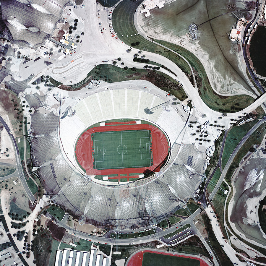 Das farbige Schrägluftbild zeigt die Dachkonstruktion des Olympiastadions und das Spielfeld.